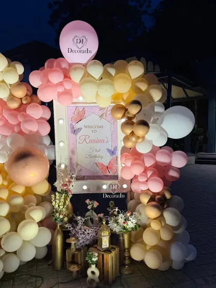 A close-up of the welcome sign, framed by a beautiful arrangement of pink, yellow, and metallic balloons.
