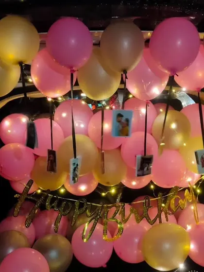 A ceiling of pink and gold balloons with photos hanging from the ribbons creates an immersive and beautiful car trunk surprise.