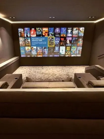 A wide shot showing the full scope of this modern theater. The design is clean and uncluttered, with the large screen as the undeniable focal point.