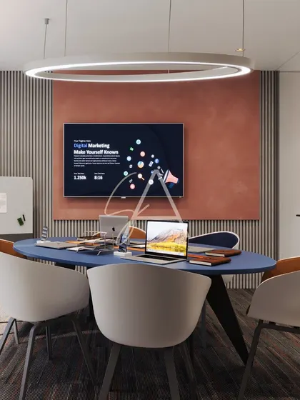 A front-on view of the meeting room, highlighting the presentation screen against a textured terracotta-colored wall. The large ring light provides even, diffused lighting for video calls and presentations.