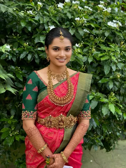 My beautiful bride Ragavi looking serene and elegant for her Muhurtham. Her subtle makeup look enhances her natural features, pairing beautifully with her pink and green Kanjeevaram saree and antique temple jewellery.