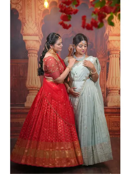 A full view of the red and mint green half-sarees, showing how beautifully they complement each other against the traditional backdrop.
