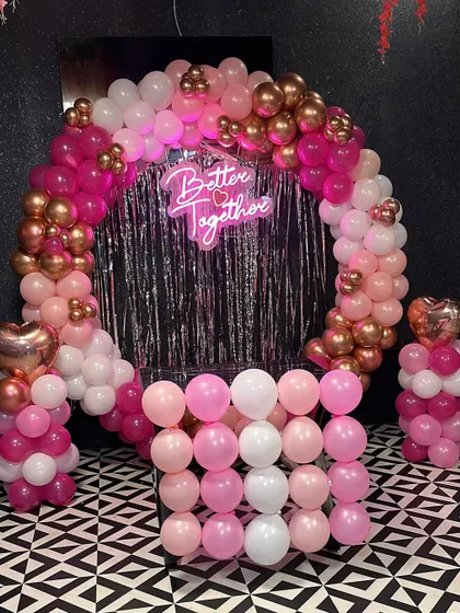 A 'Better Together' setup with a pink and gold theme. This balloon arch with a silver foil curtain is perfect for engagements, anniversaries, or bridal showers.