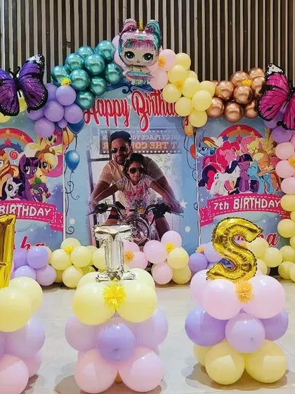 A magical butterfly and My Little Pony theme for a 7th birthday. The backdrop features a personalized photo, colorful characters, and a beautiful pastel balloon arch with large butterfly accents.