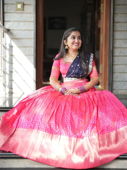 The bride seated, showcasing the beautiful flare of the pink brocade skirt and the contrasting navy blue dupatta.