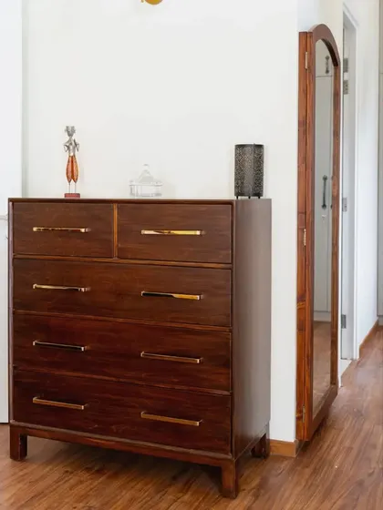 A view of the master bedroom in the Raghuvani Home, showing the chest of drawers and the unique full-length swing-out mirror at the entrance to the walk-in closet.