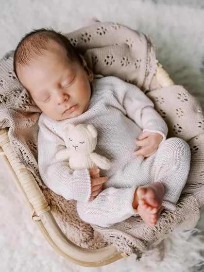 Another angle of a sweet, sleeping newborn in a cozy knit outfit, showing the different poses we can achieve even with slightly older newborns.