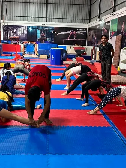 Flexibility classes are a core part of our curriculum. Here you can see a mixed group of students working on various stretches, from splits to forward folds, under the watchful eye of a coach.