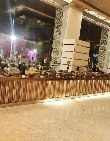 A wide view of our contemporary buffet setup inside a modern banquet hall. The long, illuminated counter provides ample space for a diverse menu, perfect for large wedding receptions.