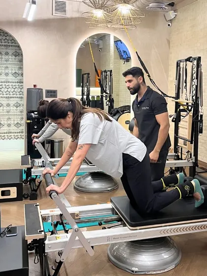 Strength in numbers. An instructor works with two clients simultaneously, providing cues to help them perfect their form on the Reformer.