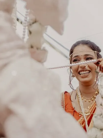 The bride's joyful smile is captured through the 'antarpat,' a cloth that separates the couple before they see each other.