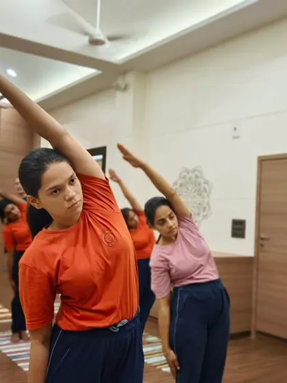 Students engage in a synchronized side stretch, a fundamental asana for improving spinal flexibility and posture. Our classes methodically move through postures to warm up and prepare the body safely.