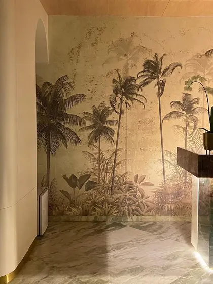 A sneak peek of the nearly finished reception area at House No. 04, featuring a stunning tropical wallpaper and a marble desk.