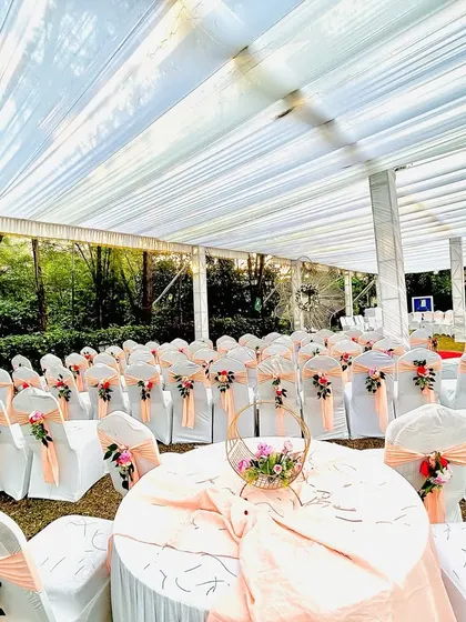 We pay attention to every detail, including guest seating. Here, we've arranged round tables and chairs with peach-colored sashes and floral accents for a wedding reception.