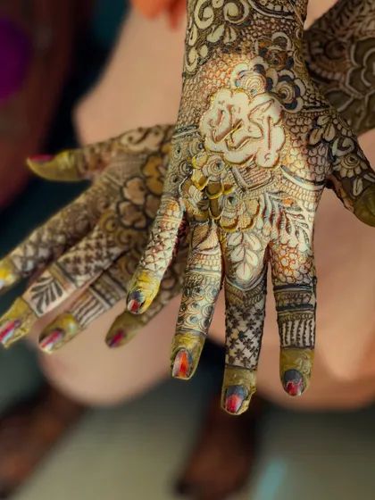 A close-up of the palm with the name "Akbar" written in elegant script, nestled within a floral motif.