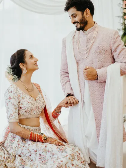 The groom gently holds his bride's hand, both looking at each other with adoration in this soft, romantic portrait.