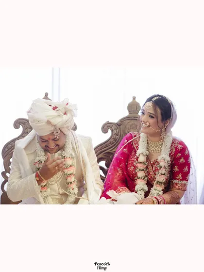 A happy, relaxed portrait of the couple seated during their wedding ceremony, sharing a lighthearted moment.