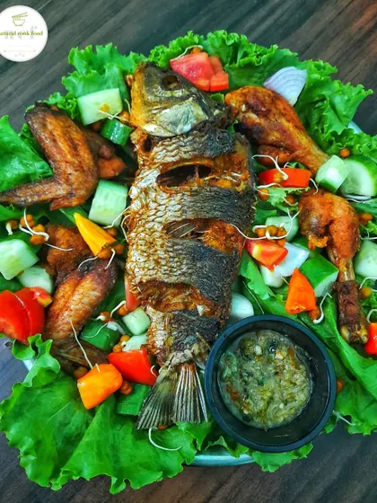 A beautiful platter with deep-fried whole fish, chicken wings, and a fresh salad, served with my special garlic and ginger chutney.