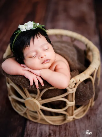 The classic 'chin on hands' pose, but this time with the baby peeking out of a rustic wicker basket.
