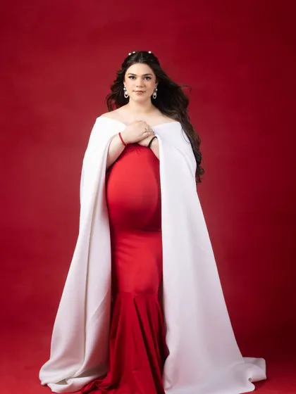 Bold, beautiful, and radiating pure elegance. This portrait, with its striking red dress and white cape, captures motherhood like never before.