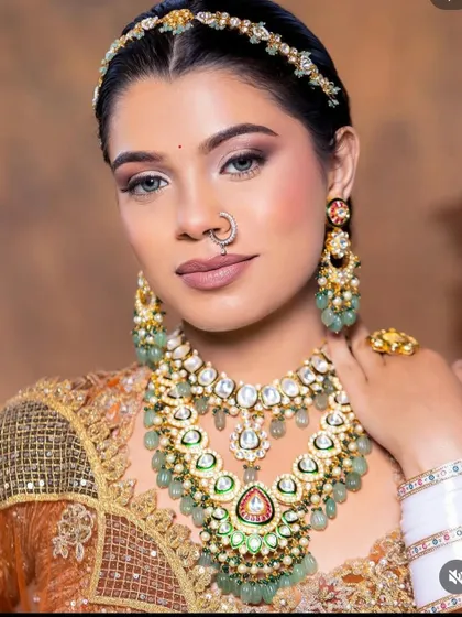 A close-up of a bride wearing a magnificent layered mint-green Kundan set with a matching matha patti and nath. The craftsmanship is evident in every detail.
