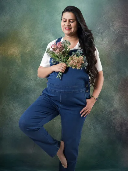 Who says maternity shoots can't be fun and casual? This expecting mother looks so happy and relaxed in denim dungarees, holding a small bouquet.