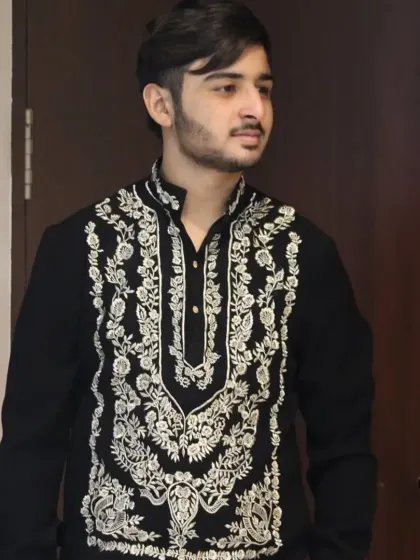 A client wearing a black kurta with intricate gold embroidery, paired with white trousers.