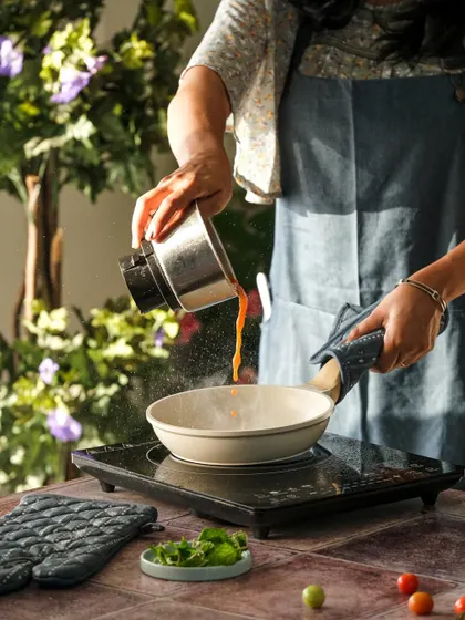 A candid action shot of a chef pouring sauce into a pan. This type of in-kitchen photography captures the energy and skill behind professional cooking, perfect for restaurant branding.