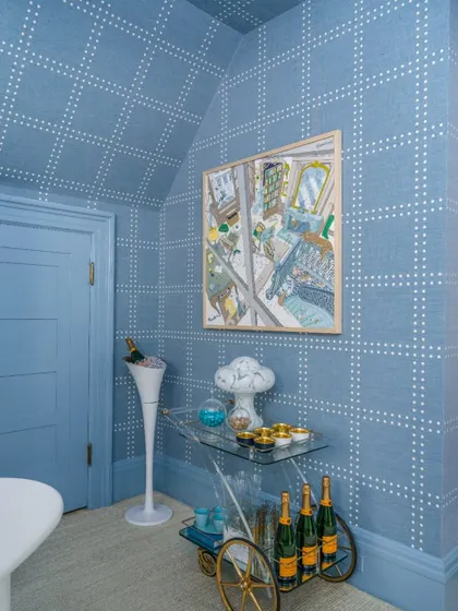 A playful yet sophisticated blue-on-blue dotted grid pattern envelops this room, covering even the ceiling. This design choice creates a cohesive and immersive environment, perfect for a chic bar or lounge area.