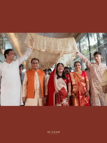 The bride's entry during a Bengali wedding, sheltered by a 'palki' held by her family. Her joyful smile as she is escorted to the mandap is a beautiful, heartwarming moment of family love and support.