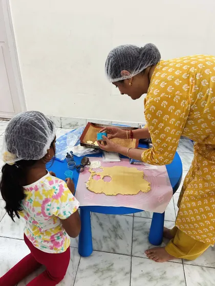 A parent helps a child use a cookie cutter to shape the dough. This baking session is a perfect blend of learning practical life skills and having fun.