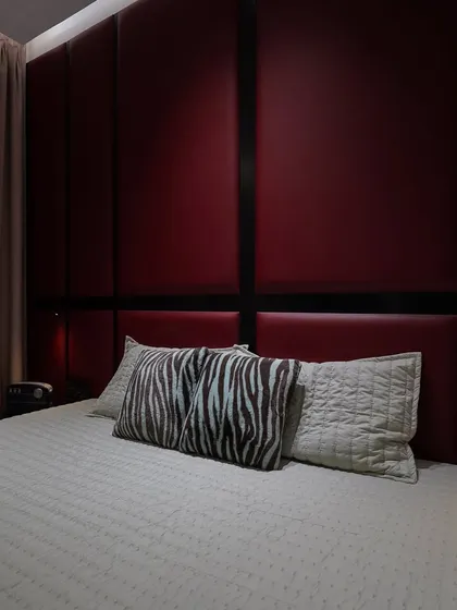 A close-up of a bold bedroom design with a floor-to-ceiling padded headboard in deep red. The black trim creates a strong graphic element, perfect for a modern and dramatic look.