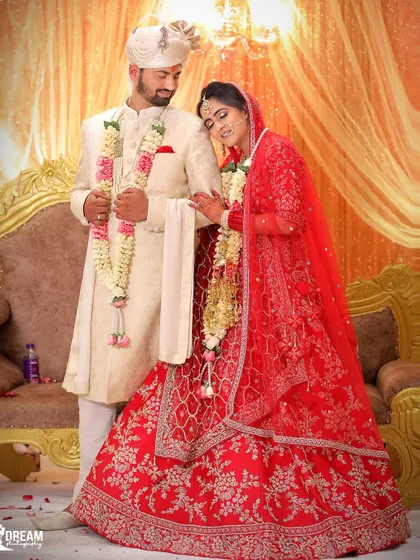 A classic portrait of the newly married couple in their red and white wedding attire, standing by the ceremonial stage.