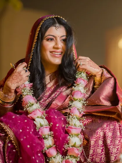 The bride's joyful expression after the varmala ceremony. Her smile is radiant, and the floral garland adds to her beauty.