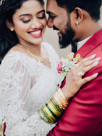 A close-up filled with smiles and affection. This image highlights the details of the bride's attire, including her traditional bangles, and the couple's joy.