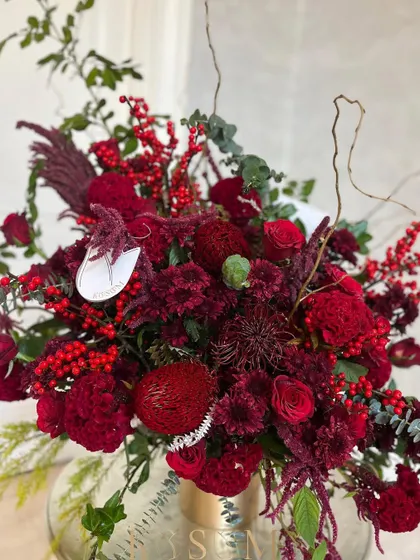 Another look at this vibrant red arrangement. The unique shapes of the banksia and pincushion flowers add an artistic and modern touch to the classic red holiday palette.