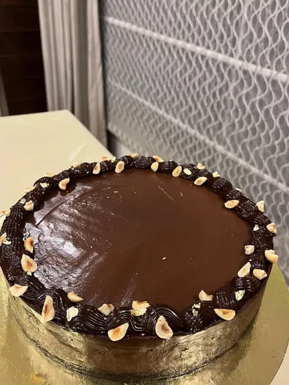 A full view of our Double Chocolate Baked Cheesecake. The glossy ganache and border of toasted hazelnuts promise pure indulgence.