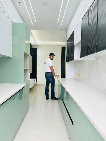 A parallel kitchen with a unique color scheme of mint green and white. The curved corner cabinets add a soft, modern touch to the design.