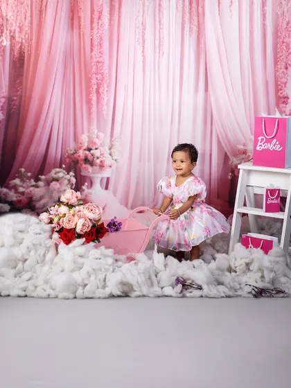 A dreamy Barbie world. This little girl, surrounded by fluffy clouds and pink floral decor, is living her princess fantasy in this beautiful themed shoot.
