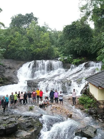 A group photo at a waterfall in Uttara Kannada, with a small temple structure nearby. Many of these natural spots are also considered sacred.