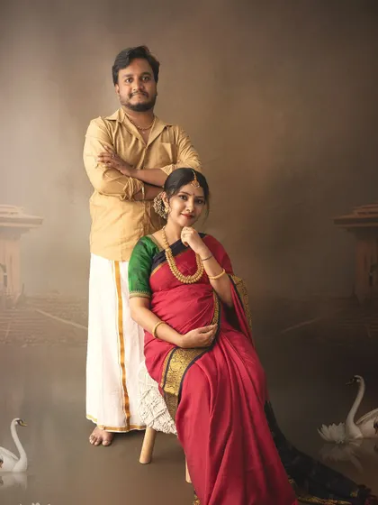 A regal portrait of an expecting couple in traditional attire, posed with painted swans to add a touch of artistic elegance.