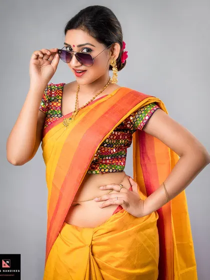 A close-up of the 'sanskari' look, where the model playfully adjusts her sunglasses. This shot highlights the fun and attitude of blending modern accessories with traditional Indian sarees.