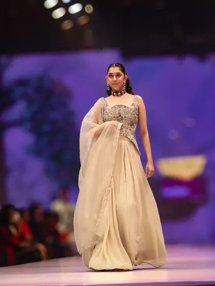 A graceful moment on the catwalk. This photo captures the gentle movement of the light, flowing fabric of this beige outfit, highlighting its understated elegance.