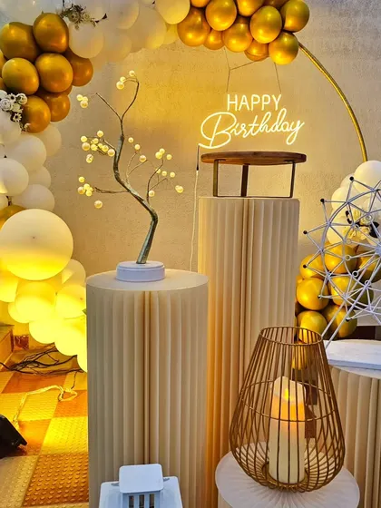 A close-up of a chic white and gold balloon arch on a rooftop, featuring elegant props like a miniature Ferris wheel and a light-up tree.