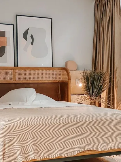 The Tierra Bed, shown here with warm, neutral bedding, creates a cozy and inviting atmosphere. The natural rattan and leather headboard adds a touch of organic elegance, perfect for a tropical-inspired retreat.