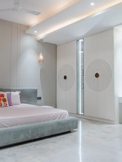 The sleek white wardrobe features a unique circular groove pattern, and one panel is a mirror with integrated shelving, a very clever and custom design feature.