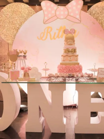 A chic Minnie Mouse first birthday setup. The large light-up "ONE" marquee letters and a rose gold color scheme give this classic theme a modern and glamorous touch.