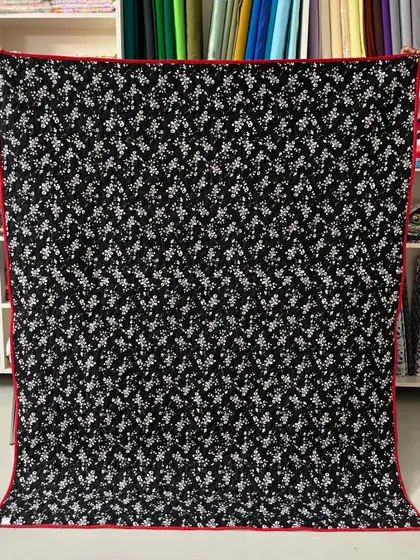 The back of a red and black star quilt, featuring a simple black and white floral print.