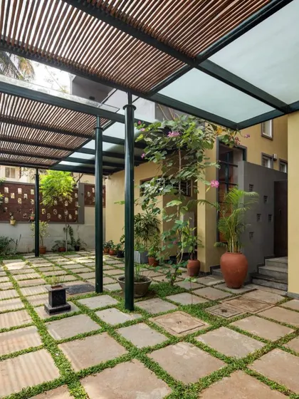 This courtyard space is designed for multiple uses, from car parking to outdoor gatherings. The greenery and semi-covered roof make it a pleasant and functional extension of the home.