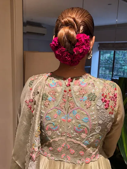 A close-up of the back of my green Anarkali, showing the intricate embroidery and my hairstyle, a classic bun adorned with a bright pink gajra.
